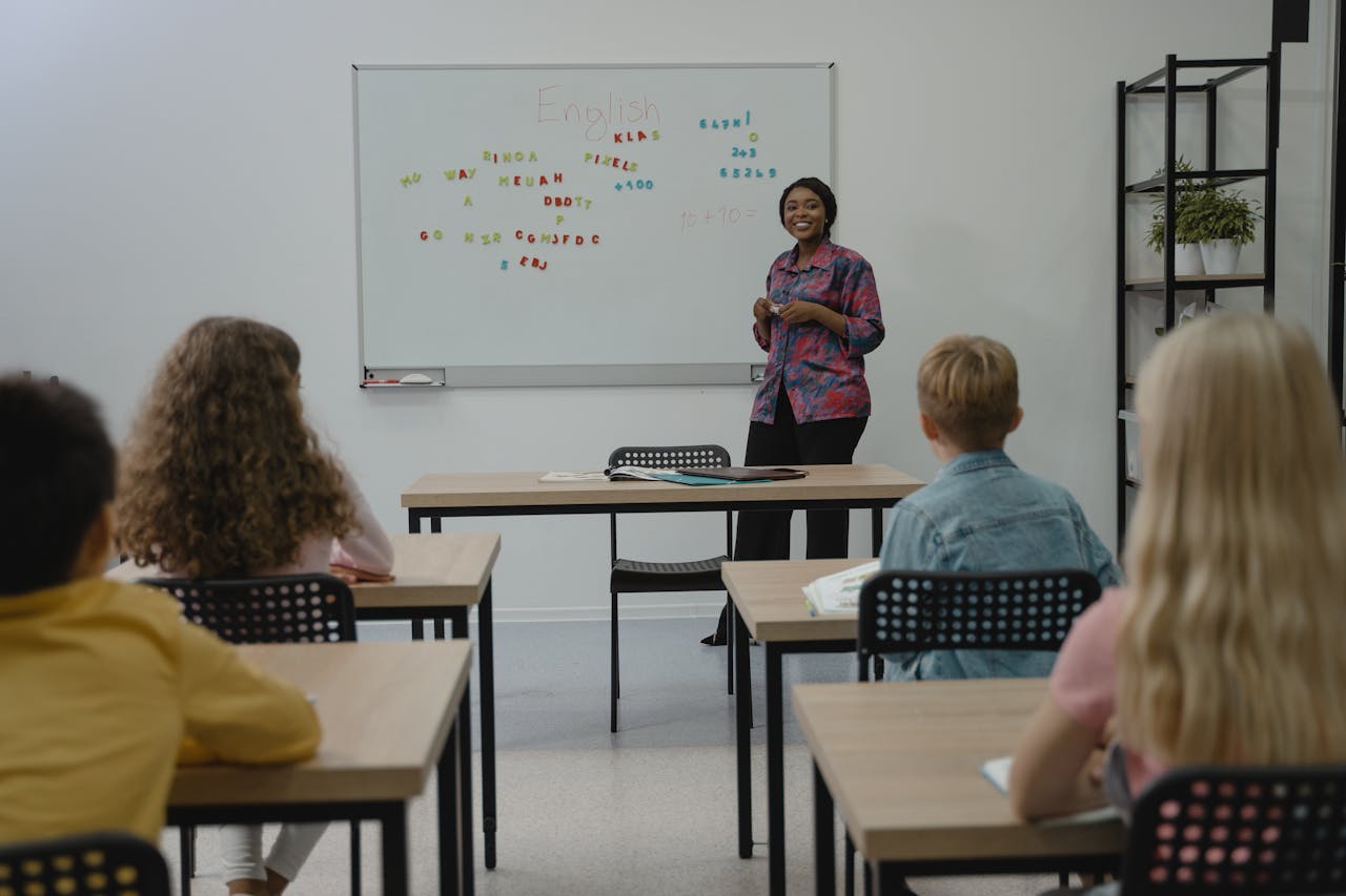 about-img A diverse group of students in an English class with a smiling teacher at the whiteboard.